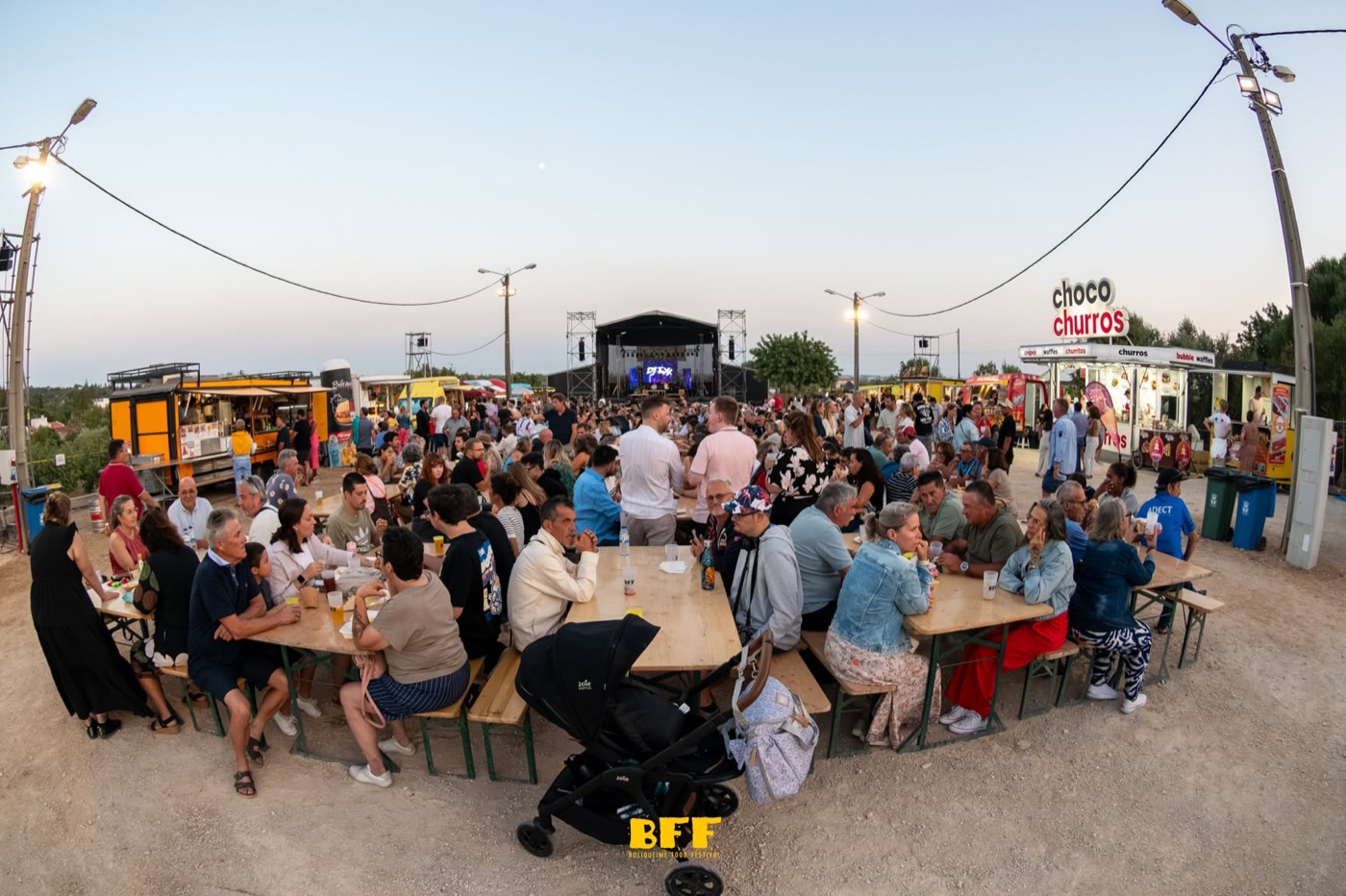 Mesas compridas cheias de gente ao fim da tarde no Boliqueime Food Festival