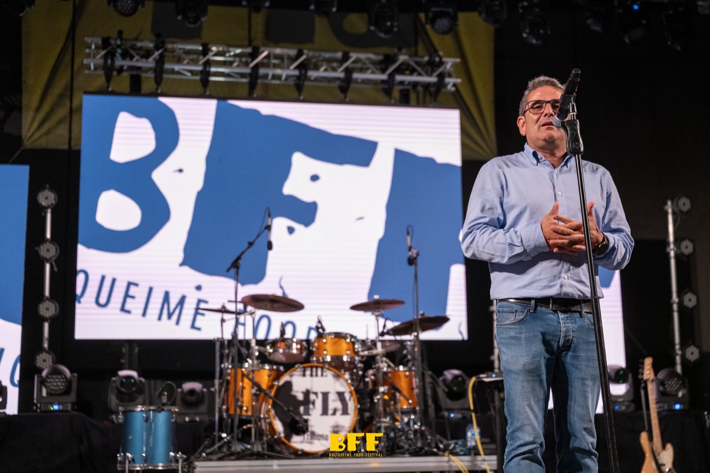 Um homem a falar ao microfone no palco do festival