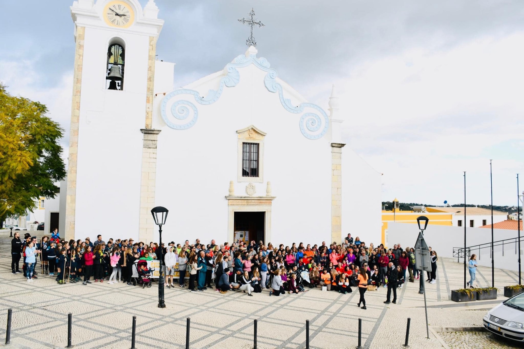 Multidão reunida em frente a uma igreja branca