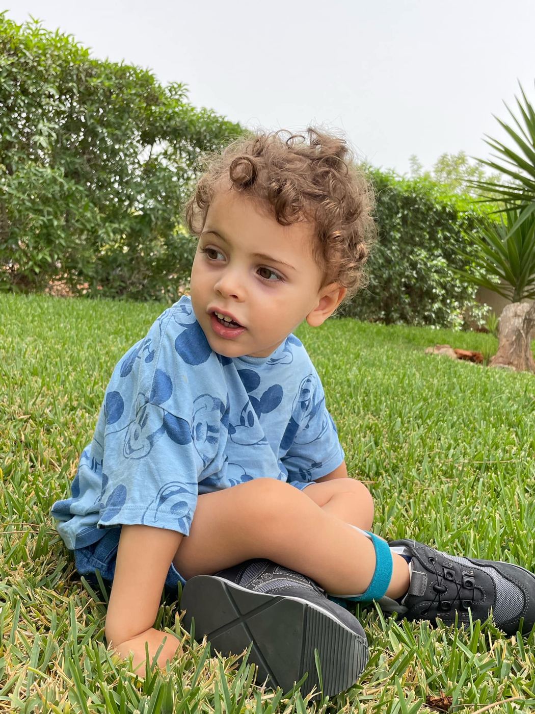 O Martim sentado na relva, de camisola azul